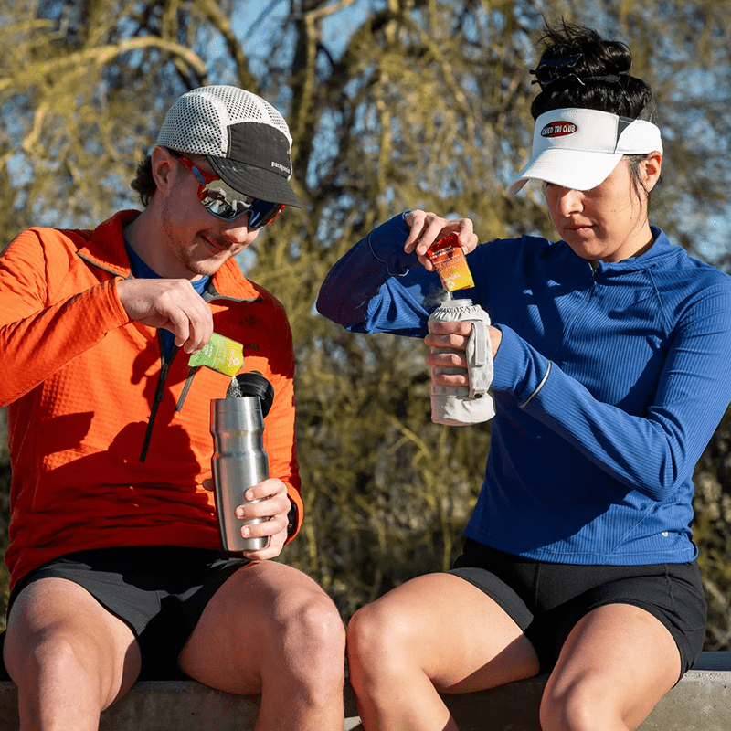 Two runners pouring Tailwind mix into water bottles